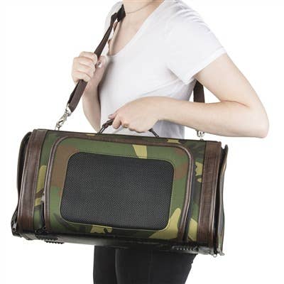 Camouflage dog carrier bag with front mesh door and top handle, carried by person